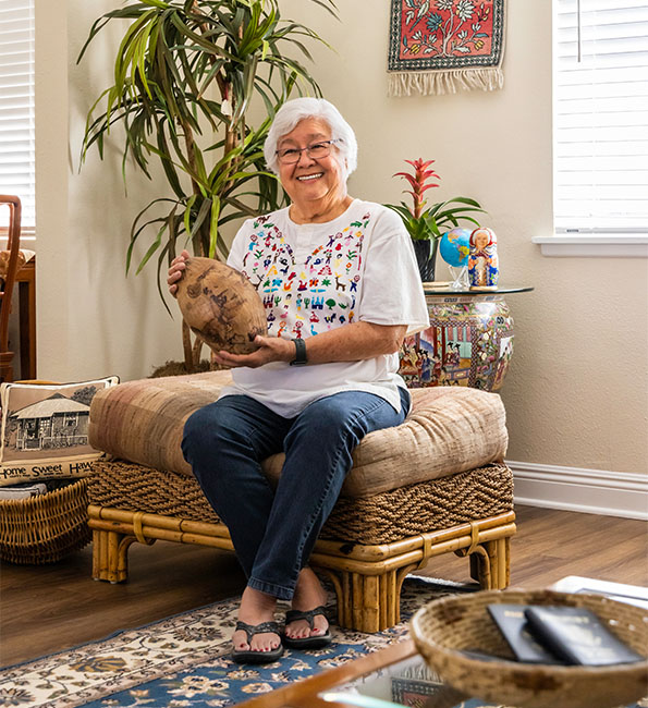 Janet sitting on ottoman holding a souvenir from her travels